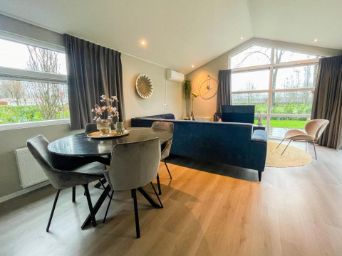 Moderne opholdsstue i Wood Lodge på Holiday park Molenvelden i Holland med store vinduer og elegant indretning.