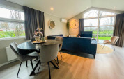 Salon moderne à la Wood Lodge du Holiday park Molenvelden, Pays-Bas, avec de grandes fenêtres et une déco élégante.