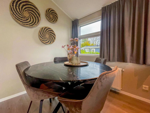 Zona pranzo con tavolo rotondo in marmo nero nella Wood Lodge, Holiday park Molenvelden, Paesi Bassi.