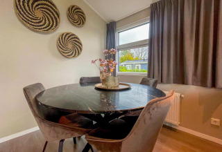 Dining area with round black marble table and velvet chairs in Wood Lodge, Holiday park Molenvelden, Netherlands.