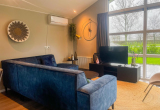Soggiorno accogliente nella Wood Lodge al Holiday park Molenvelden, Olanda, con divano blu e grandi finestre.