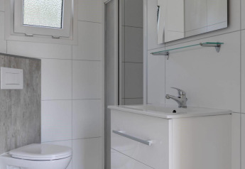 Baño moderno con inodoro, lavabo y espejo en Wood Lodge, Holiday park Molenvelden en los Países Bajos.