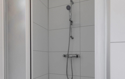 Moderne bruser i en hvid flisebelagt kabine på Wood Lodge, Holiday park Molenvelden, Holland.