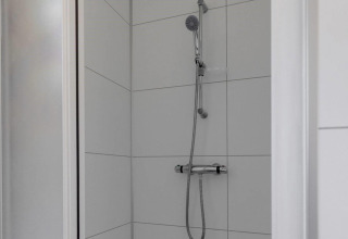 Modern shower with white tiled walls at Wood Lodge, Holiday park Molenvelden, Netherlands.