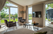 Helles Wohnzimmer in Villa Veldzicht, Ferienpark Molenvelden, Niederlande, mit modernen Möbeln und großen Fenstern.