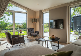 Bright living area in Villa Veldzicht, Holiday park Molenvelden, Netherlands, with large windows and modern decor.