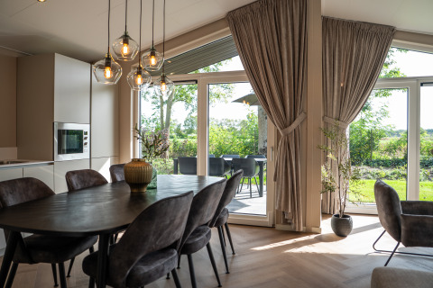 Comedor moderno con grandes ventanales y vistas al jardín en Villa Veldzicht, Holiday park Molenvelden.