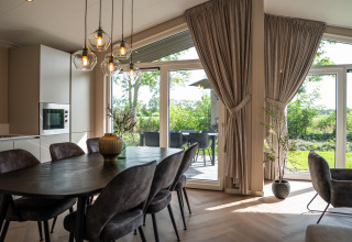 Moderne spisestue med store vinduer, der åbner ud til have, Villa Veldzicht, Holiday park Molenvelden.