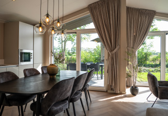 Modern dining area with large windows and garden view at Villa Veldzicht, Holiday park Molenvelden.