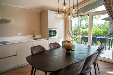 Moderne lodgekøkken og spiseområde i Villa Veldzicht på Holiday park Molenvelden, Holland, med udsigt.