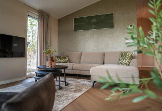 Salón moderno en Villa Veldzicht del parque Holiday Molenvelden, Países Bajos, con sofá beige y decoración elegante.