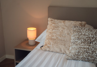 Dormitorio en Villa Veldzicht, Holiday park Molenvelden, Países Bajos, con lámpara moderna y cojines decorativos.