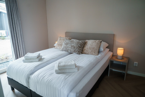 Dormitorio moderno en Villa Veldzicht, Holiday park Molenvelden, Países Bajos, con cama doble cómoda.