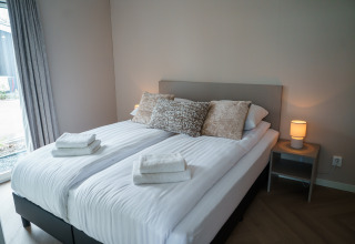 Camera moderna a Villa Veldzicht, Holiday park Molenvelden, Paesi Bassi, con letto matrimoniale e lampade.