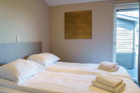 Moderne soveværelse i Villa Veldzicht med to enkeltsenge, rene håndklæder og kunst på væggen, Holiday park Molenvelden.
