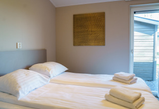 Modern bedroom at Villa Veldzicht with two single beds, fresh towels and wall art, Holiday park Molenvelden.