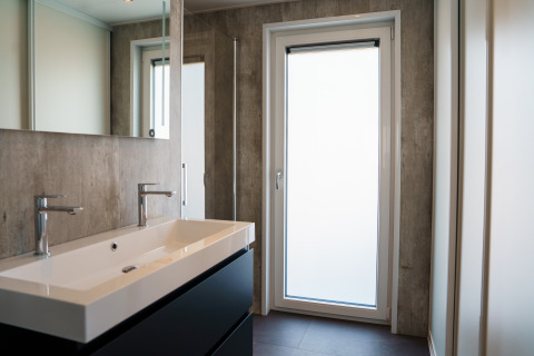 Baño moderno con lavabo doble, espejos y puerta grande en Villa Veldzicht, Holiday park Molenvelden.