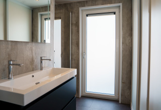 Moderne badeværelse med dobbelthåndvask, store spejle og stor dør i Villa Veldzicht, Molenvelden.