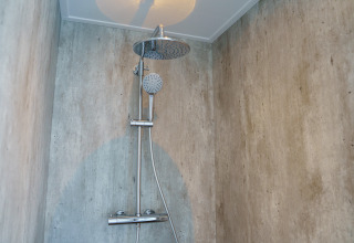Moderne Dusche mit Betonwänden in der Villa Veldzicht im Ferienpark Molenvelden, Niederlande.
