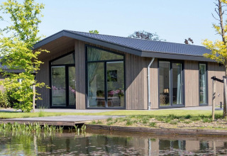 Moderne lodge med store vinduer og veranda ved en sø, Villa Waterzicht Luxe met Hottub 4, Molenvelden, Holland.