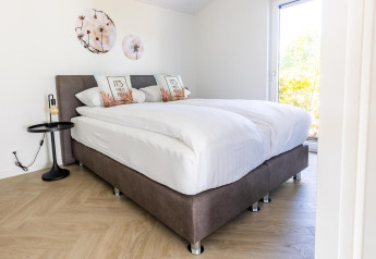 Dormitorio moderno con cama doble, obras de arte en la pared y mucha luz en Villa Waterzicht Luxe, Molenvelden.