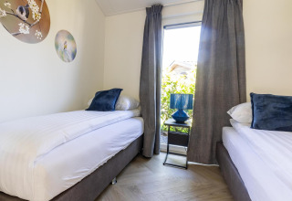 Lyst værelse på Villa Waterzicht Luxe met Hottub 4, Holiday park Molenvelden, to senge og vindue.