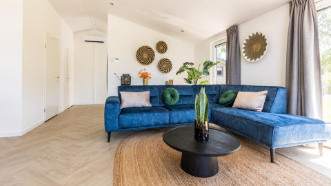 Sala moderna en Villa Waterzicht Luxe con sofá azul y decoración en Holiday park Molenvelden, Países Bajos.