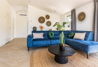 Salon élégant à la Villa Waterzicht Luxe avec canapé bleu et plantes au Holiday park Molenvelden, Pays-Bas.