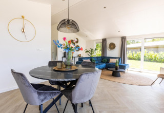 Zona de estar moderna en Villa Waterzicht Luxe con sofá azul y comedor en Molenvelden, Países Bajos.