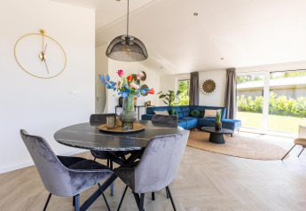 Zona giorno moderna a Villa Waterzicht Luxe con divano blu e tavolo da pranzo a Molenvelden, Paesi Bassi.