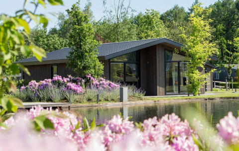 Villa Waterzicht Luxe con Hottub 6 al parco vacanze Molenvelden, Paesi Bassi, accanto a stagno e fiori.