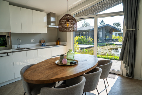 Moderne køkken og spiseområde med udsigt til have og sø i Villa Waterzicht Luxe met Hottub 6, Molenvelden.
