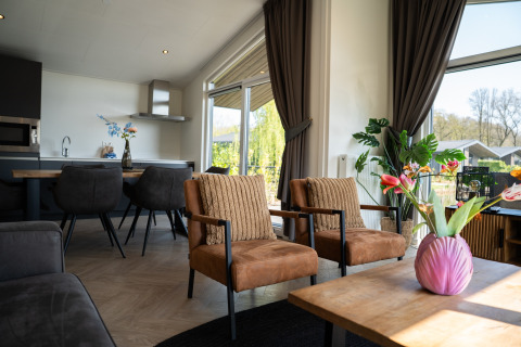 Moderne stue i Villa Waterzicht Luxe med Hottub 6, Holiday park Molenvelden, med store vinduer og udsigt.