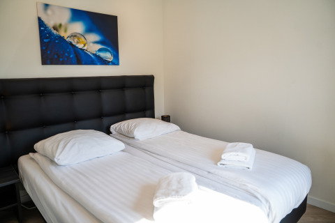 Dormitorio moderno en Villa Waterzicht Luxe con dos camas individuales, sábanas blancas y arte mural.