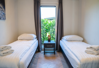 Moderne soveværelse på Villa Waterzicht Luxe med to enkeltsenge og vindue, Holiday park Molenvelden.