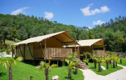 Lodges in tela a Can Bora Lodges, un villaggio turistico in Catalogna, Spagna, tra colline verdi e palme.