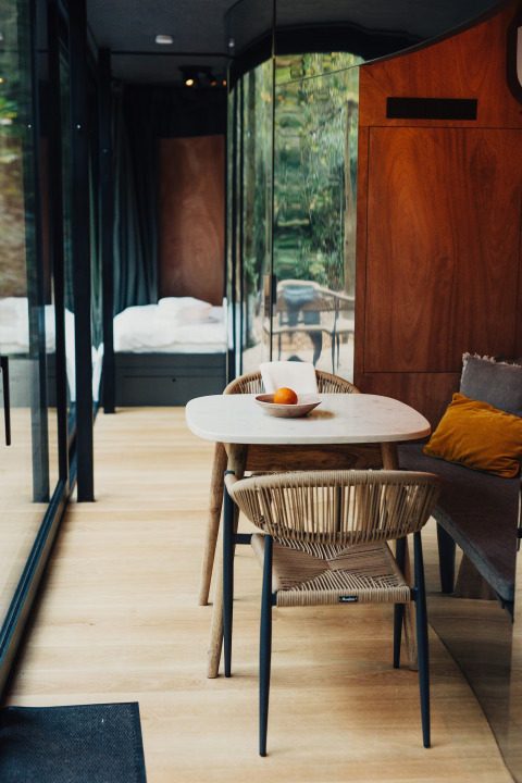 Moderne lodgeinteriør i Slowlodge Echo på Zomerlicht i Holland med spisebord, stole og glasvæg.