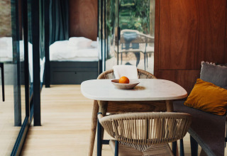 Moderne lodgeinteriør i Slowlodge Echo på Zomerlicht i Holland med spisebord, stole og glasvæg.