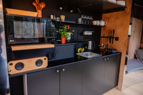 Kitchenette noire moderne avec micro-ondes, évier et herbes au Slowlodge Echo de Zomerlicht, Pays-Bas.