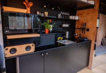 Kitchenette noire moderne avec micro-ondes, évier et herbes au Slowlodge Echo de Zomerlicht, Pays-Bas.