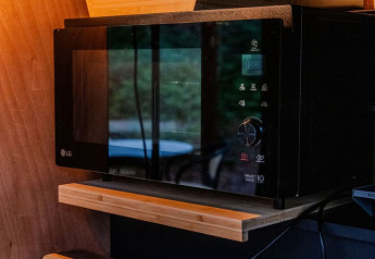 Angolo accogliente con microonde e altoparlante allo Slowlodge Echo di Zomerlicht, Paesi Bassi, illuminato da luce calda.