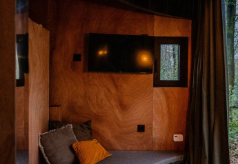 Moderne lodge-interiør i Slowlodge Echo ved Zomerlicht, med træpaneler, sofa og vindue til naturen.