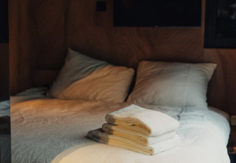 Camera accogliente con letto matrimoniale, cuscini e asciugamani piegati a Slowlodge Echo, Zomerlicht, Paesi Bassi.