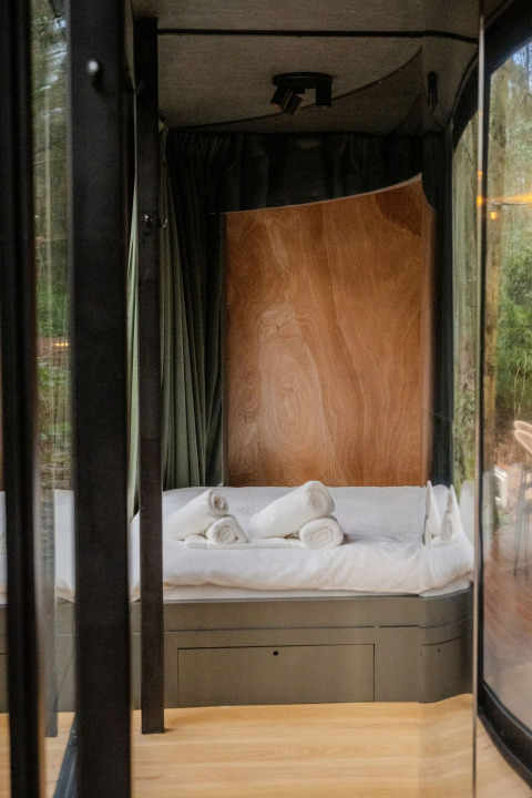 Moderne, hyggelig seng med rullede håndklæder i et lodgeværelse på Slowlodge Echo, Zomerlicht, Holland.