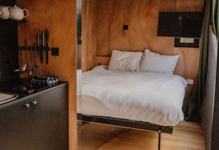 Chambre de lodge moderne avec intérieur en bois, lit confortable et cuisine à Slowlodge Echo, Zomerlicht, Pays-Bas.