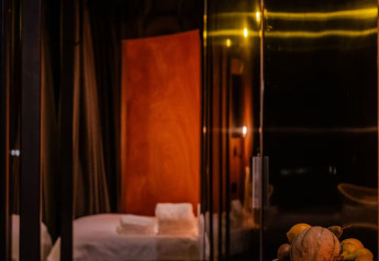 Interno accogliente di Slowlodge Echo a Zomerlicht, Paesi Bassi, con letto e libri su un tavolo di marmo.