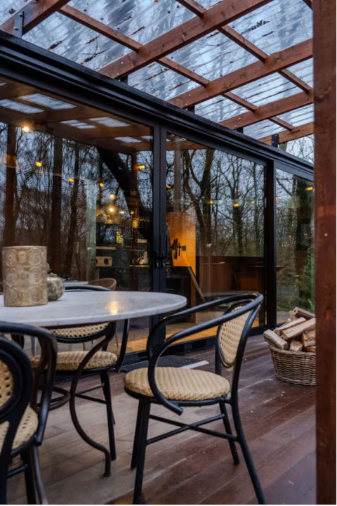 Udendørs spiseområde ved Slowlodge Echo på Zomerlicht, Nederlandene, med glasdør og træpergola.
