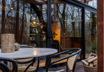 Udendørs spiseområde ved Slowlodge Echo på Zomerlicht, Nederlandene, med glasdør og træpergola.
