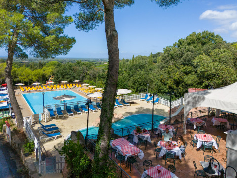 Udsigt over swimmingpool og udendørs restaurant på Sandaya Le Pianacce feriested i det solrige Toscana, Italien.