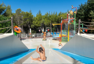 Børn leger på en vandlegeplads med rutsjebaner i Sandaya Le Pianacce feriepark i Toscana, Italien.